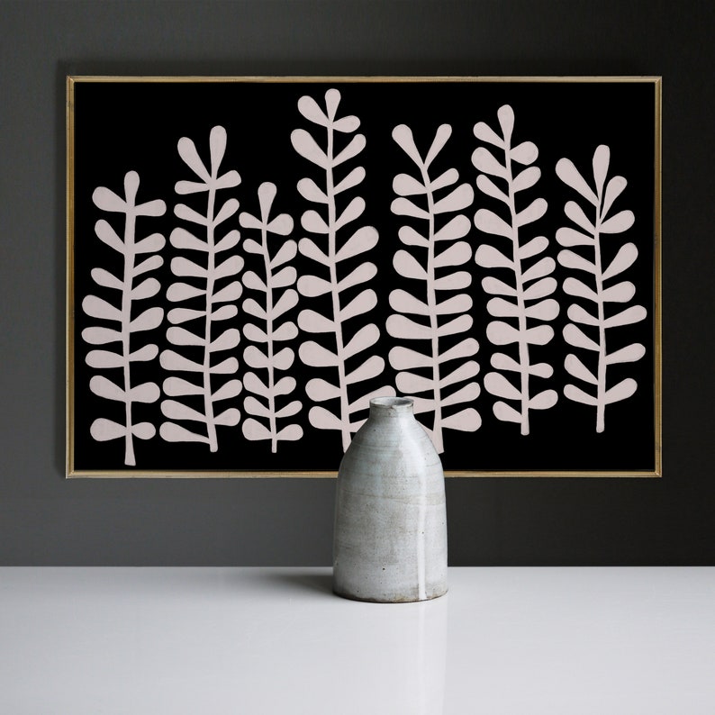 Puede incluir: Una impresi&oacute;n de arte abstracto en blanco y negro con un dise&ntilde;o estilizado de hojas de helecho rosas. La impresi&oacute;n est&aacute; enmarcada en un marco dorado fino y se muestra sobre una superficie blanca con un jarr&oacute;n de cer&aacute;mica gris.