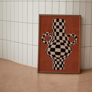 May include: A framed print of a black and white checkered vase with two handles on a terracotta background.