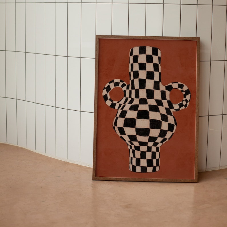 May include: A framed print of a black and white checkered vase with two handles on a terracotta background.