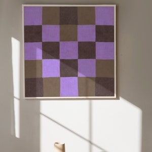 May include: A framed abstract painting with a checkered pattern in shades of purple and brown.