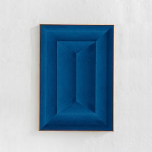 May include: A blue square painting with a series of concentric squares creating a 3D effect. The painting is framed in a thin, gold-colored frame.