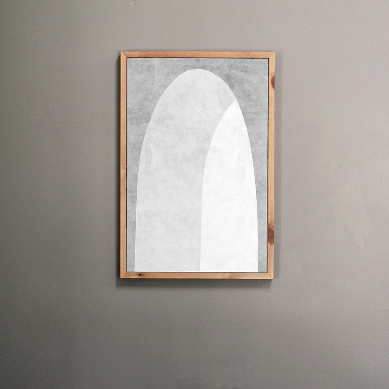 Peut inclure: Une impression d'art abstrait encadr&eacute;e avec un motif blanc et gris de deux arches qui se chevauchent. L'impression est dans un cadre en bois clair.