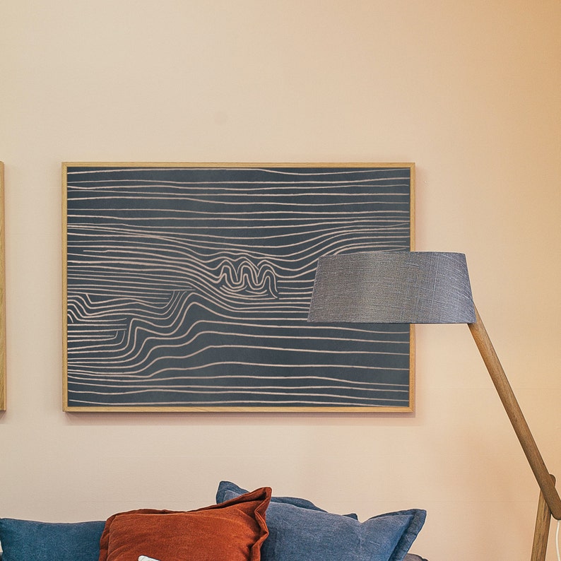 May include: A framed abstract art print with a black background and white lines creating a wavy pattern. The print is hanging on a light peach wall.