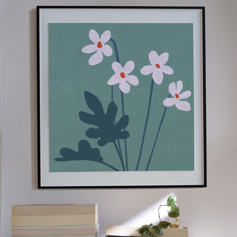 May include: A framed print with a minimalist design featuring five white flowers with orange centers on a teal background. The flowers are stylized and have a simple, modern aesthetic. The print is framed in a black frame.