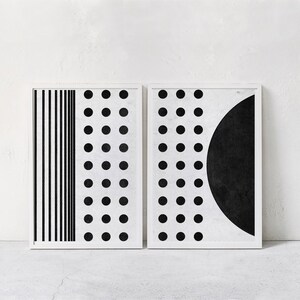 Puede incluir: Dos impresiones enmarcadas en blanco y negro con patrones geom&eacute;tricos. La impresi&oacute;n de la izquierda tiene rayas verticales negras y un campo de puntos negros. La impresi&oacute;n de la derecha tiene un campo de puntos negros y un semic&iacute;rculo negro.