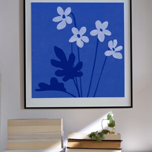 Pu&ograve; includere: Una stampa incorniciata di uno sfondo blu con fiori bianchi e foglie blu scuro. I fiori sono stilizzati e hanno cinque petali ciascuno.