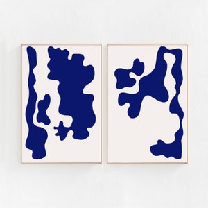 May include: Two framed abstract art prints with a white background and blue abstract shapes. The shapes are organic and resemble clouds or water.