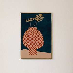 May include: A framed illustration of a red and white checkered vase with a gold stem and two gold leaves on a dark blue background.