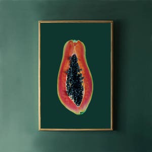 May include: A close-up of a papaya cut in half, revealing the black seeds inside. The papaya is a vibrant orange-red color and is set against a dark green background.