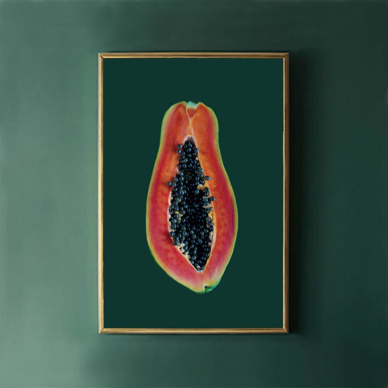 May include: A close-up of a papaya cut in half, revealing the black seeds inside. The papaya is a vibrant orange-red color and is set against a dark green background.