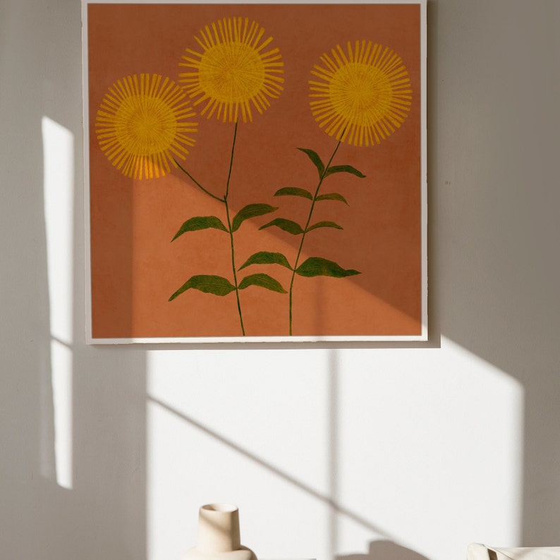 May include: A framed print of three yellow flowers with green stems on a terracotta background.