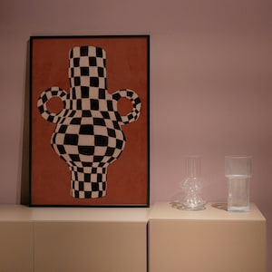 May include: A framed print of a black and white checkered vase with rounded handles on a red background.