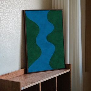 May include: A framed abstract painting with a blue river-like shape winding through a green background.
