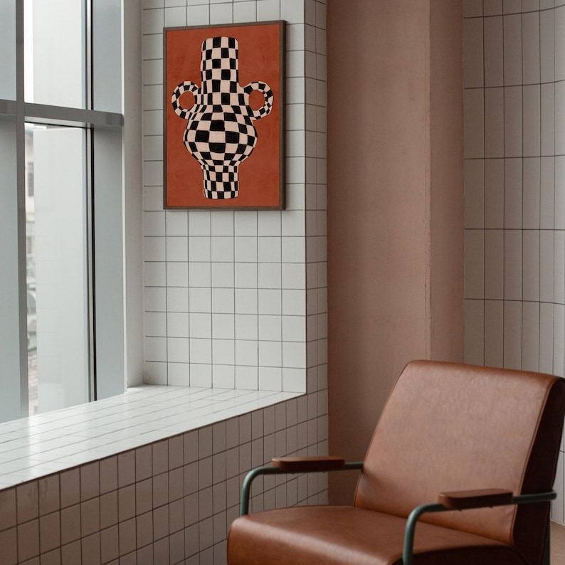 May include: A framed print of a black and white chequered vase with rounded handles against a red background.
