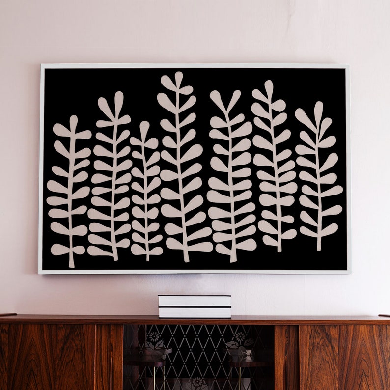 Puede incluir: Una impresi&oacute;n enmarcada en blanco y negro de un dise&ntilde;o abstracto estilizado de un bosque con hojas rosas. La impresi&oacute;n est&aacute; colgada en una pared rosa claro sobre un armario de madera.