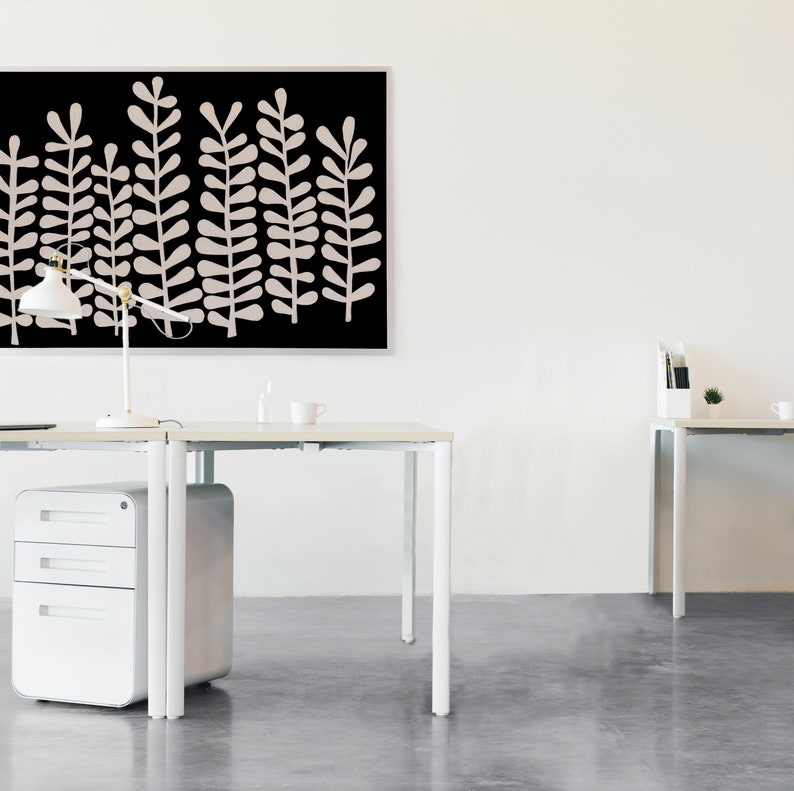 Puede incluir: Dos escritorios blancos con patas de metal blanco y un archivador blanco. Una impresi&oacute;n enmarcada en negro con un dise&ntilde;o abstracto blanco cuelga en la pared detr&aacute;s de los escritorios.