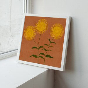 May include: A framed print of three yellow flowers with green stems on a brown background.