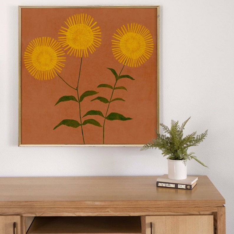 May include: A framed print of three yellow flowers with green stems on a terracotta background.