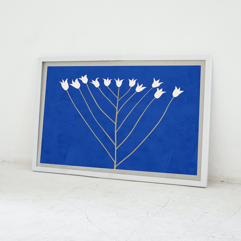 May include: A framed print of a stylized white flower arrangement on a blue background. The flowers are arranged in a symmetrical pattern, resembling a tree with branches.
