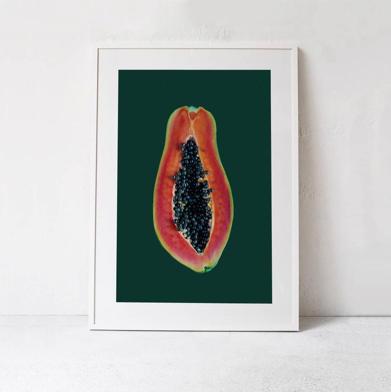 May include: A halved papaya with black seeds against a dark green background. The papaya is a vibrant orange-red color.