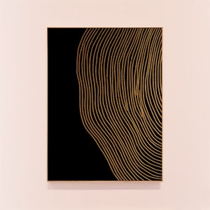 Puede incluir: Un lienzo enmarcado en negro con un dise&ntilde;o abstracto dorado de l&iacute;neas onduladas.