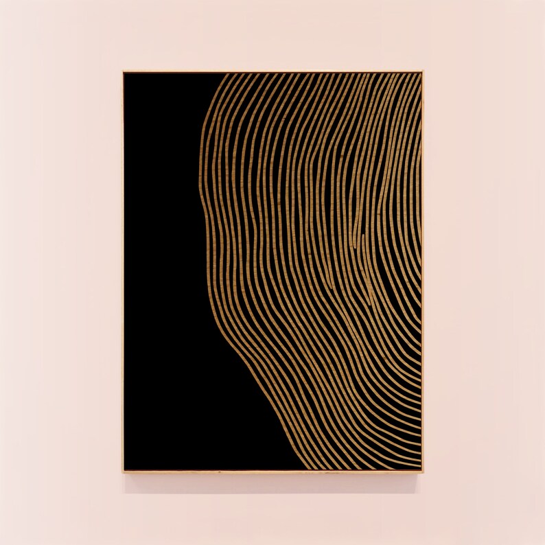 Puede incluir: Un lienzo enmarcado en negro con un dise&ntilde;o abstracto dorado de l&iacute;neas onduladas.