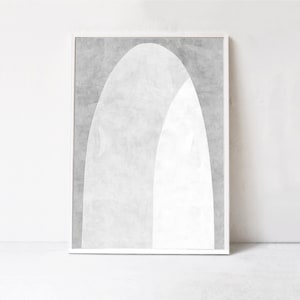 Peut inclure: Une impression d'art abstrait encadr&eacute;e avec un sch&eacute;ma de couleurs blanc et gris. L'impression pr&eacute;sente deux arches qui se chevauchent, cr&eacute;ant un design moderne et minimaliste.