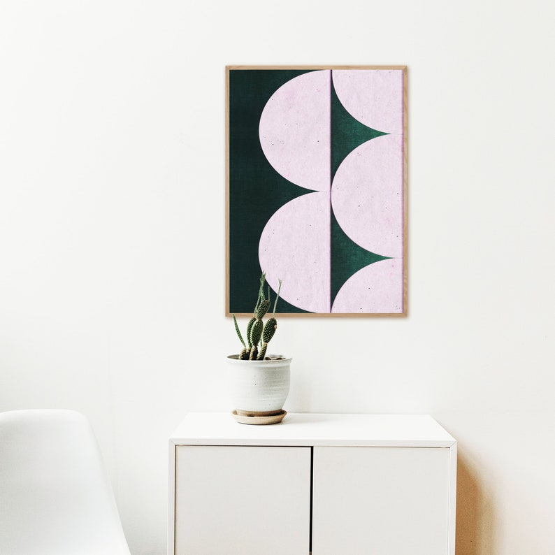 May include: A framed print with a geometric design featuring overlapping pink and dark green semi-circles.