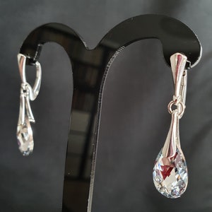 May include: A pair of silver dangle earrings with clear crystal teardrop shaped stones.
