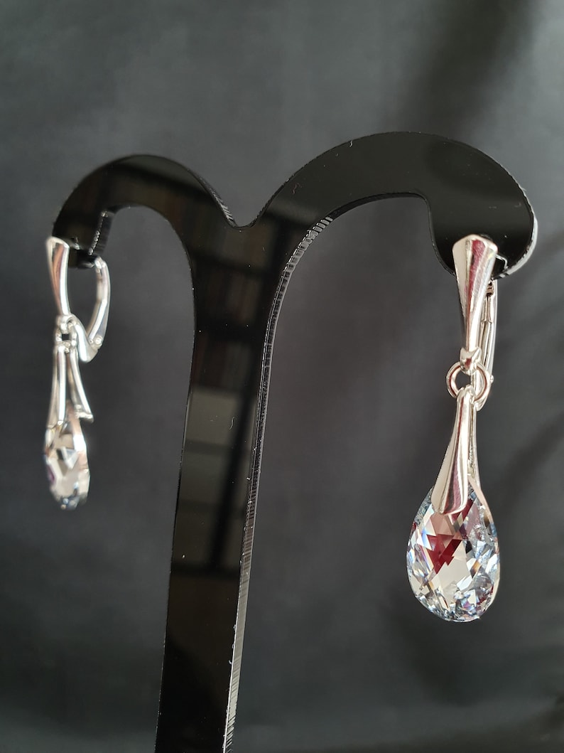 May include: A pair of silver dangle earrings with clear crystal teardrop shaped stones.