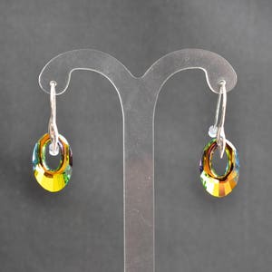 Peut inclure: Une paire de boucles d'oreilles créoles en argent avec des accents de cristal vert et jaune irisés.