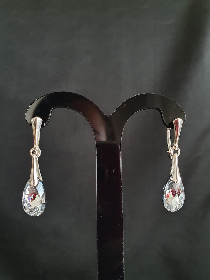 May include: A pair of silver dangle earrings with clear crystal teardrop shaped stones.