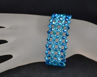May include: A blue crystal bracelet with a geometric design. The bracelet is made of small, faceted beads that are strung together in a repeating pattern.