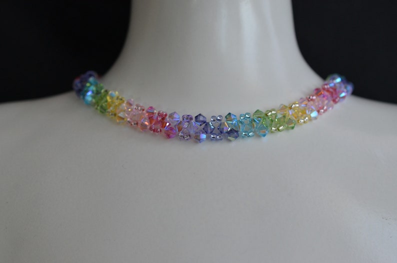 May include: A rainbow crystal necklace with iridescent beads. The necklace is made of small, faceted crystals in shades of red, orange, yellow, green, blue, indigo, and violet.