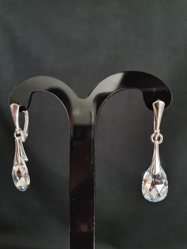 May include: A pair of silver dangle earrings with clear crystal teardrop shaped stones.