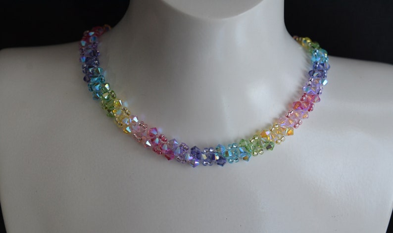 May include: A rainbow-colored crystal bead necklace. The beads are arranged in a gradient pattern, starting with purple and ending with green.