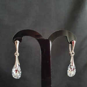 May include: A pair of silver teardrop earrings with clear crystal stones.
