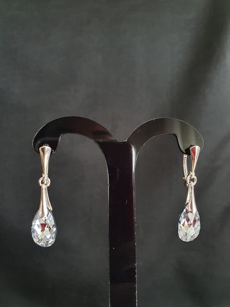 May include: A pair of silver teardrop earrings with clear crystal stones.
