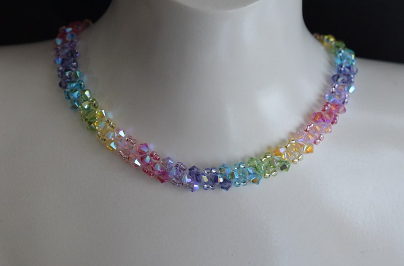 May include: A rainbow crystal necklace with iridescent beads. The necklace is made of small, faceted beads that are strung together in a graduated pattern, starting with purple and ending with green.