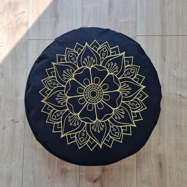 May include: Black round meditation cushion with a gold mandala design. The mandala features a large flower with intricate details.