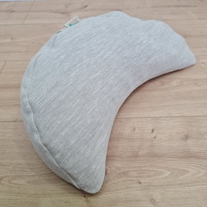 May include: A crescent-shaped meditation cushion made of gray hemp fabric. The cushion has a label that says "HEMP" with a green leaf logo.