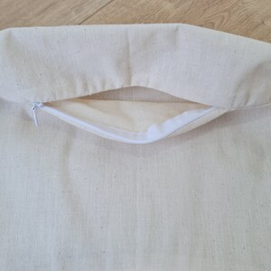 May include: A white cotton pillow cover with a zipper opening. The cover is made of a soft, natural fabric and has a subtle texture.