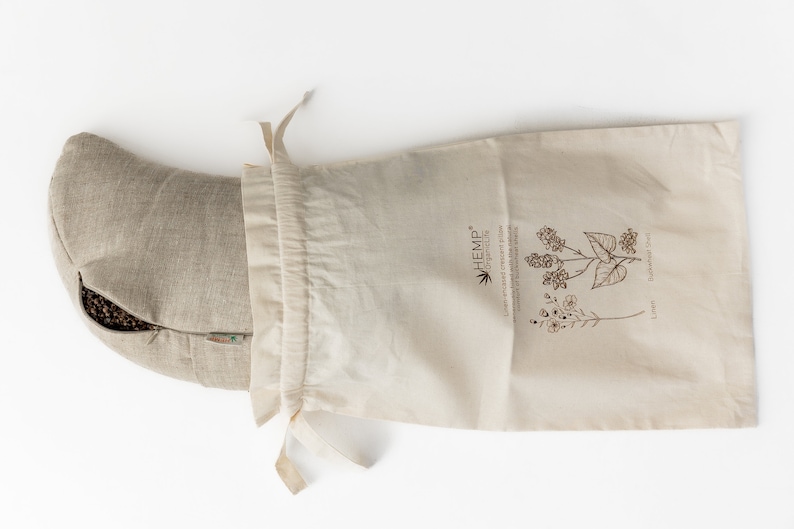 May include: A beige hemp pillow filled with buckwheat hulls, in a natural cotton drawstring bag. The bag has a label that reads "HEMP* ORGANIC LIFE" and features illustrations of hemp and flax plants.