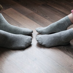 May include: Two pairs of gray socks on a wooden floor. The socks are made of a soft, comfortable material.