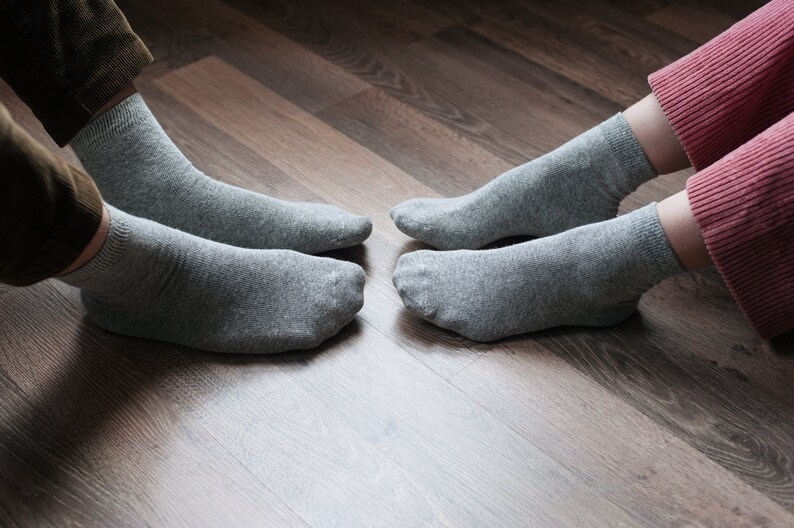 May include: Two pairs of gray socks on a wooden floor. The socks are made of a soft, comfortable material.