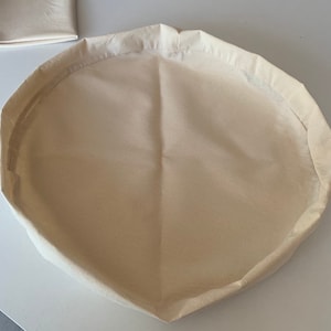 May include: A white cotton round storage basket with a folded edge.