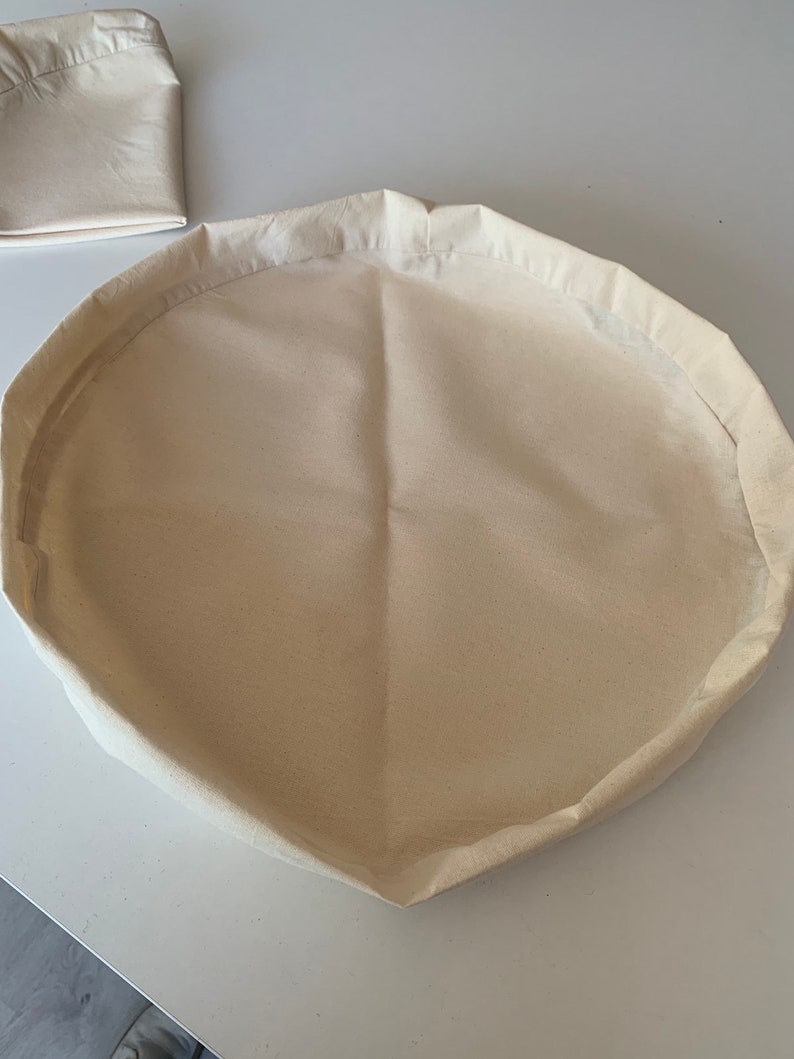 May include: A white cotton round storage basket with a folded edge.