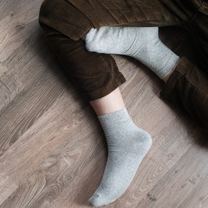 May include: A pair of gray socks with brown corduroy pants. The socks are ankle-length and made of a soft, comfortable material.