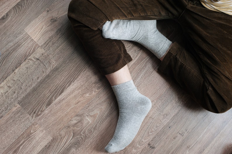 May include: A pair of gray socks with brown corduroy pants. The socks are ankle-length and made of a soft, comfortable material.