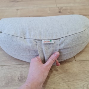 May include: A light gray hemp meditation cushion with a zipper closure and a label that reads "HEMP".